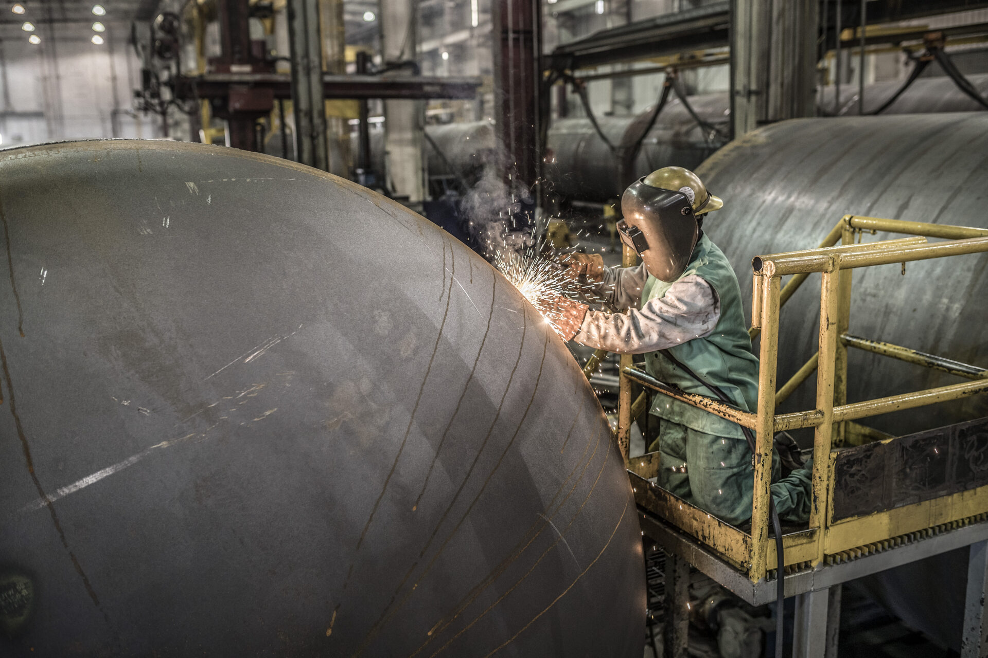 A welder works on equipment at a railyard